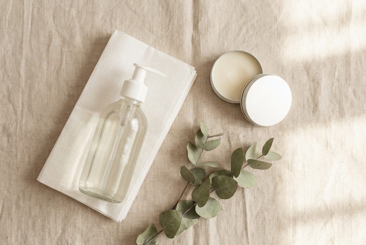 Simple tattoo aftercare supplies: fragrance-free liquid soap, paper towels and an open tin of balm